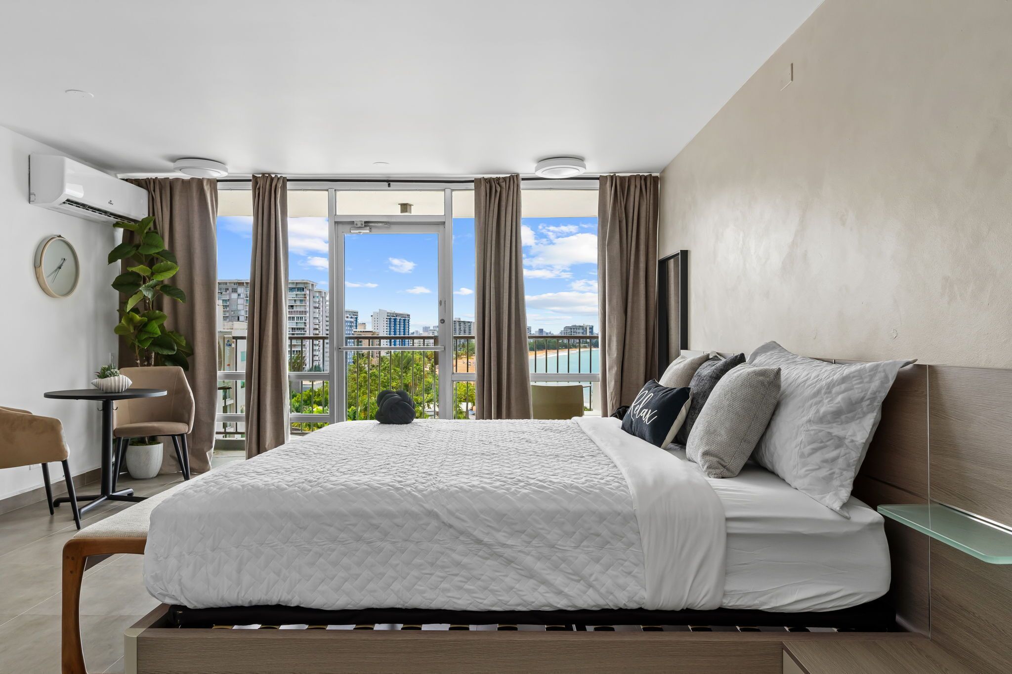 A modern hotel room with a large bed, a desk, and a view of the city.