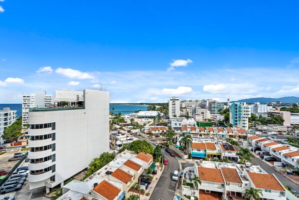 A coastal cityscape with modern buildings, a clear blue sky, and a view of the sea. - ESJ hosted by PMI (Carolina)