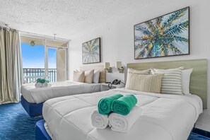 Una habitació d'hotel amb dos llits, un balcó i obra d'art a les parets.