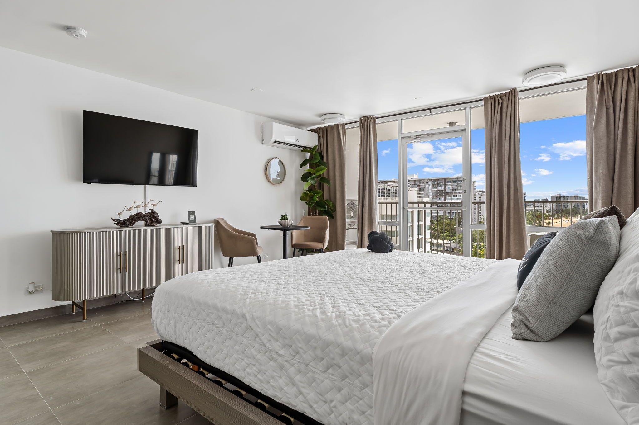 Ett modernt hotellrum med en stor säng, en platt-TV, ett skrivbord och utsikt över staden.