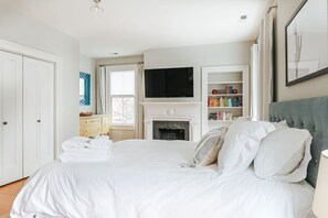 Une chambre à coucher avec un lit, une cheminée, un téléviseur et une bibliothèque.