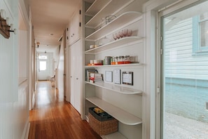 A hallway with wooden flooring, white cabinets, and shelves with various items. - Hilltop Hideaway (Staunton)