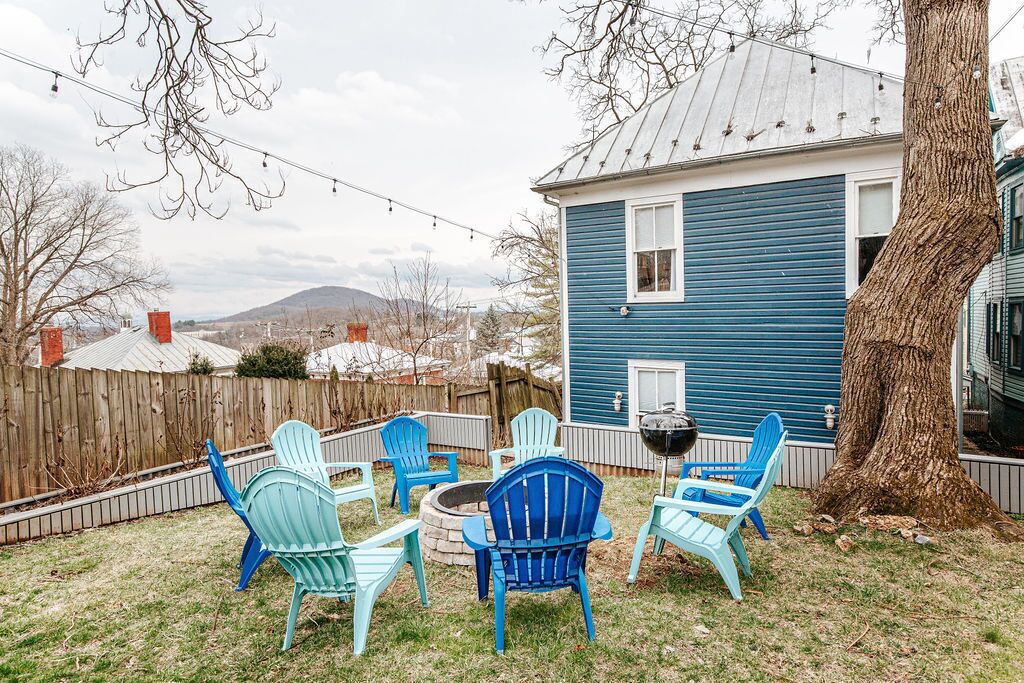 A backyard with outdoor seating, a barbecue grill, and a blue house.