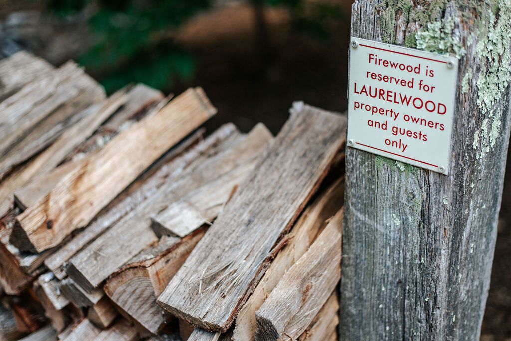 A stack of firewood with a sign indicating it is reserved for Laurelwood property owners and guests only.