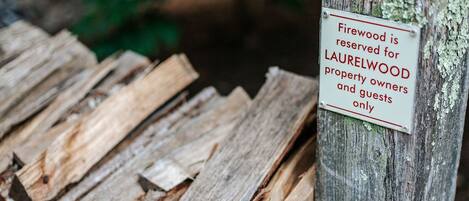 A stack of firewood with a sign indicating it is reserved for Laurelwood property owners and guests only.
