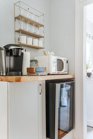 Una kitchenette con cafetera, microondas y un refrigerador pequeño.