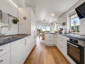 Eine moderne Küche mit weißen Schränken, Holzboden und Blick ins Freie.