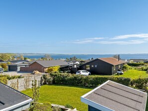 Ein Wohngebiet mit Häusern, einem Auto und Blick auf das Meer.