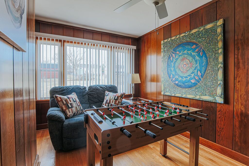 A cozy room with a foosball table, a comfortable sofa, and a large painting on the wall.