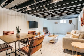 A modern interior with a dining area, a sofa, a TV, and a ceiling with exposed beams. - Lewis Mountain Retreat (Charlottesville)