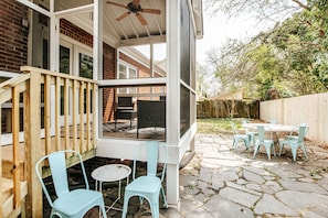 A covered patio with a wooden deck, outdoor seating, and a screened area. - Lewis Mountain Retreat (Charlottesville)