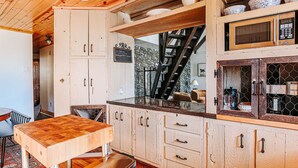 Een keuken met houten kastjes, een houten tafel en een roestvrijstalen spoelbak.