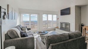 A modern living room with a grey sofa set, a coffee table, and a fireplace. - Mountain View Vista (Nellysford)