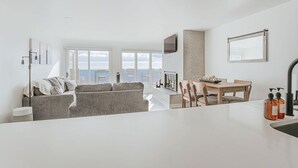 A modern living room with a sofa, a dining table with chairs, and a kitchen area with a sink and countertop. - Mountain View Vista (Nellysford)