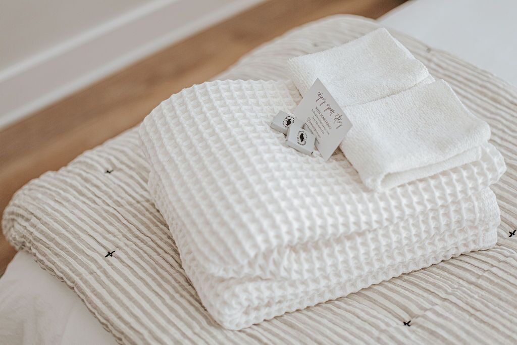 Une serviette blanche, soigneusement pliée, avec une étiquette attachée à un coussin à rayures.