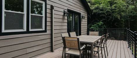 A deck with a table and chairs, a railing, and a building with windows and doors.