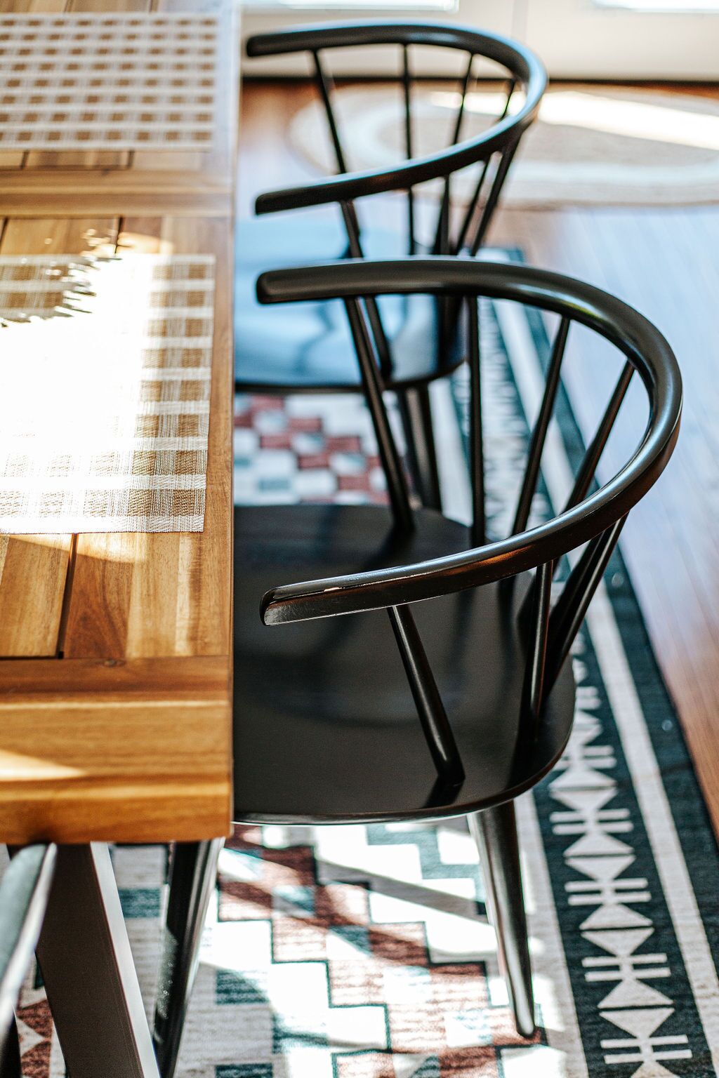 A dining table with a black chair and a woven placemat.