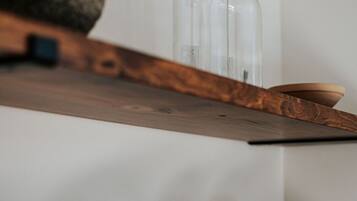 A wooden shelf with stacked white plates and two clear glass bottles.