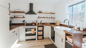 Uma cozinha moderna com armários brancos, bancadas de madeira e prateleiras embutidas.