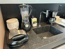 Una encimera de cocina con una licuadora, una cafetera y un cubo de basura.