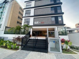 Un edificio moderno de varios pisos, con una escalera que conduce a la entrada, y un letrero que dice 'GET BY SIDE'.