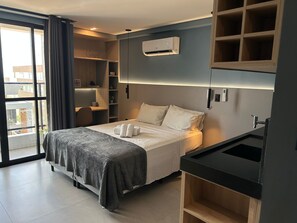 Ein Hotelzimmer mit Bett, Schreibtisch, Kleiderschrank und Blick ins Freie.