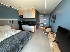 A compact hotel room with a bed, a small kitchenette, a dining area, and a TV. - Bela Hospedagem - Get By Side  (João Pessoa)
