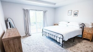 A bedroom with a bed, a wooden dresser, a nightstand, a lamp, a ceiling light, and a window with curtains. - New Sequim Condo Near Olympic Discovery Trail, Golf & Lavender Farms (Sequim)
