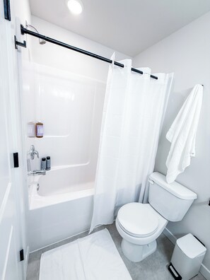 Un baño con bañera, inodoro y cortina de ducha.