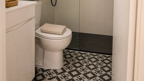 A bathroom with a toilet, a shower, and a patterned floor. - Room-tranquil 19th-century Farmhouse Roo (Lousa)