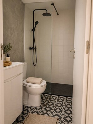 Un baño con inodoro, ducha y suelo estampado.