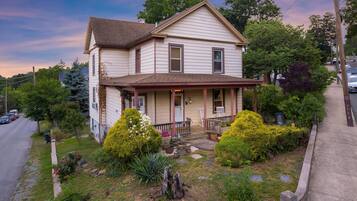 A two-story house with a front porch, a driveway, and a well-maintained garden.
