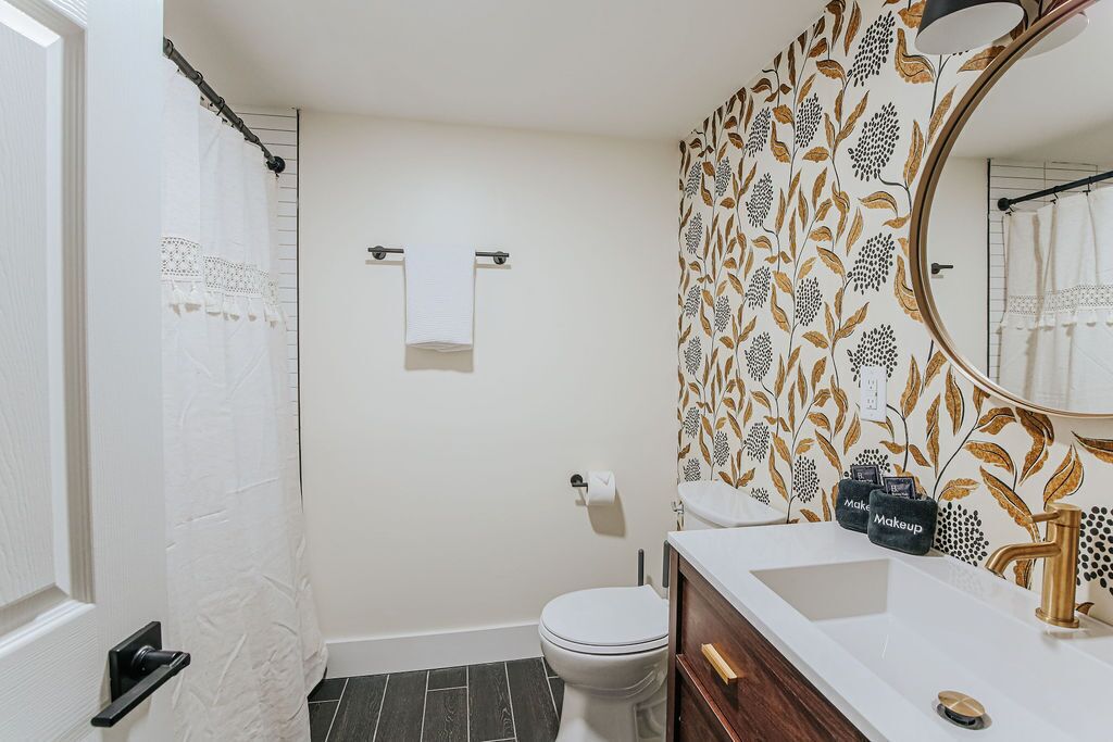 A bathroom with a white toilet, a sink with a gold faucet, and a mirror.