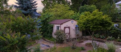 A small house surrounded by lush greenery and a paved pathway.