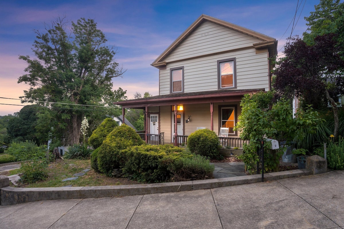 A two-story house with a porch, a mailbox, and a well-maintained garden.