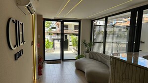 Eine moderne Hotelhalle mit einer Couch, einer Rezeption und einem großen Glasbalkon zur Außenwelt.