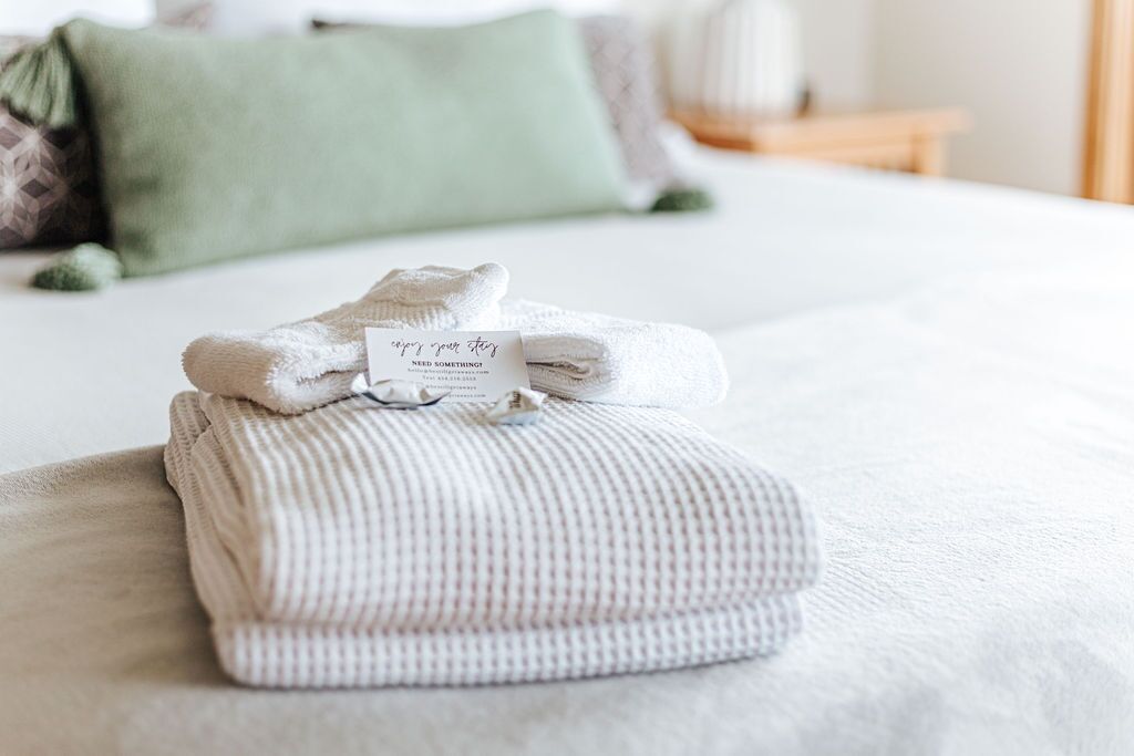 A neatly folded white towel with a tag on a bed in a hotel room.