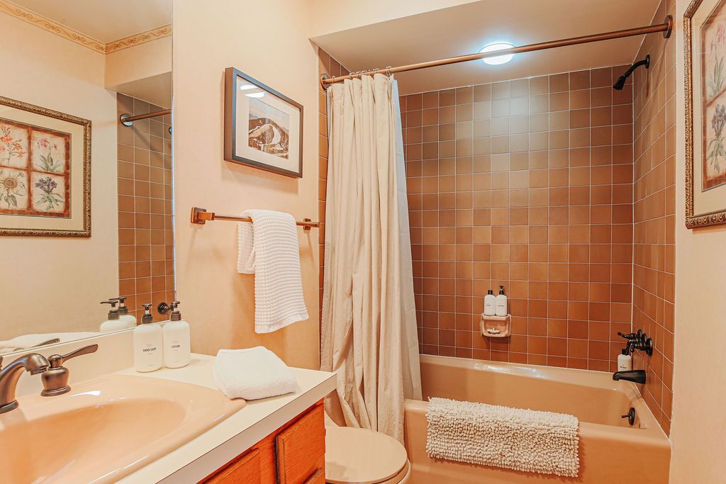 A bathroom with a sink, toilet, and bathtub. There are towels and toiletries on the counter.