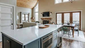 A spacious kitchen with a large island, wooden ceiling, and a fireplace. - Pilotview Hollow (Nellysford)