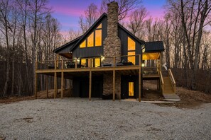 A modern house with a stone chimney, large windows, and a wooden deck. - Pilotview Hollow (Nellysford)