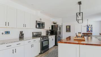 A modern kitchen with white cabinets, stainless steel appliances, and a wooden countertop.