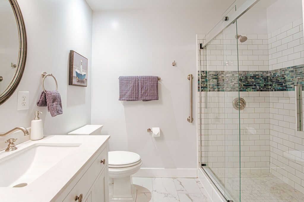 A bathroom with a white sink, toilet, and a glass-enclosed shower area.