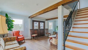 Ein geräumiges Wohnzimmer mit einer Holztreppe, einem großen Fenster und einer Glastür.