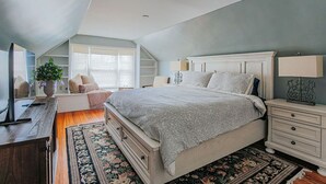 Ein Schlafzimmer mit einem großen Bett, einem Schreibtisch, einem Stuhl, einer Kommode und einem Nachttisch.