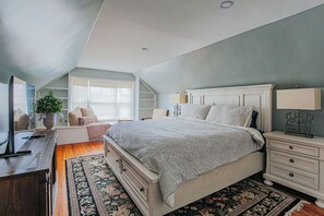 Un dormitorio con una cama grande, un escritorio, una silla, un aparador y una mesita de noche.