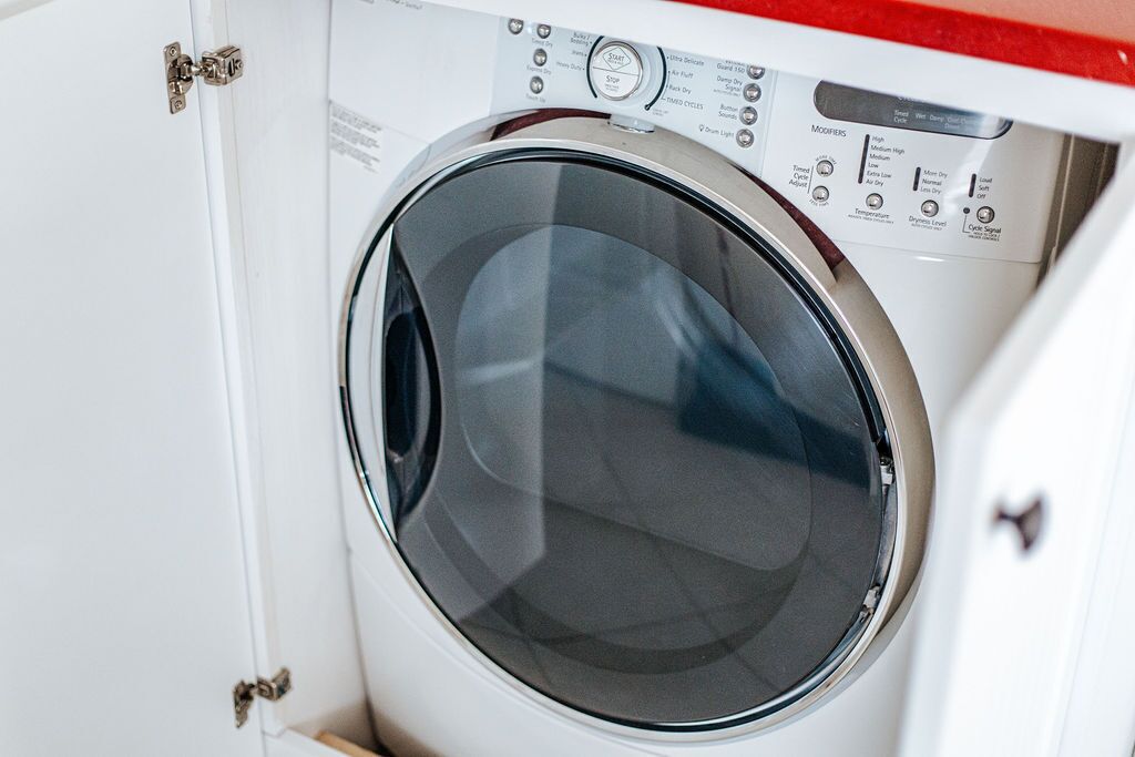 A front view of a white washing machine with control panel and door lock.