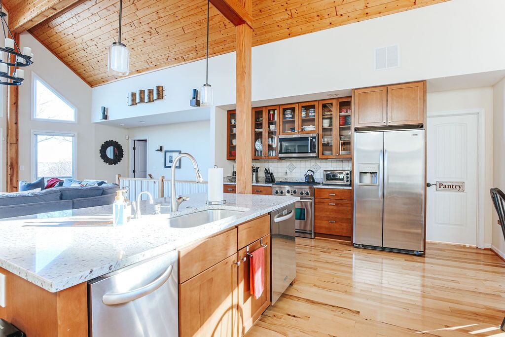 A modern kitchen with wooden cabinets, stainless steel appliances, and a large island with a sink.
