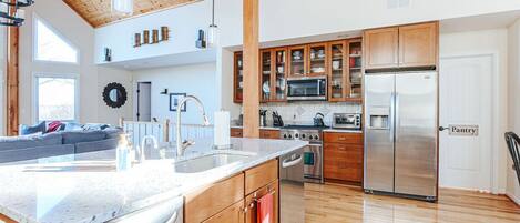 A modern kitchen with wooden cabinets, stainless steel appliances, and a large island with a sink.