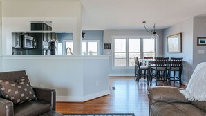 A modern kitchen with built-in appliances, a dining area with a wooden table and chairs, and a cozy living room with a leather sofa. - Ridgeview Retreat (Staunton)