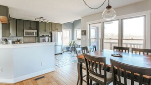 A modern kitchen with a central island, wooden flooring, and a dining area with a large table and chairs. - Ridgeview Retreat (Staunton)